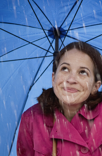 Femme sous un parapluie bleu symbolisant la maintenance de la toiture et des gouttières